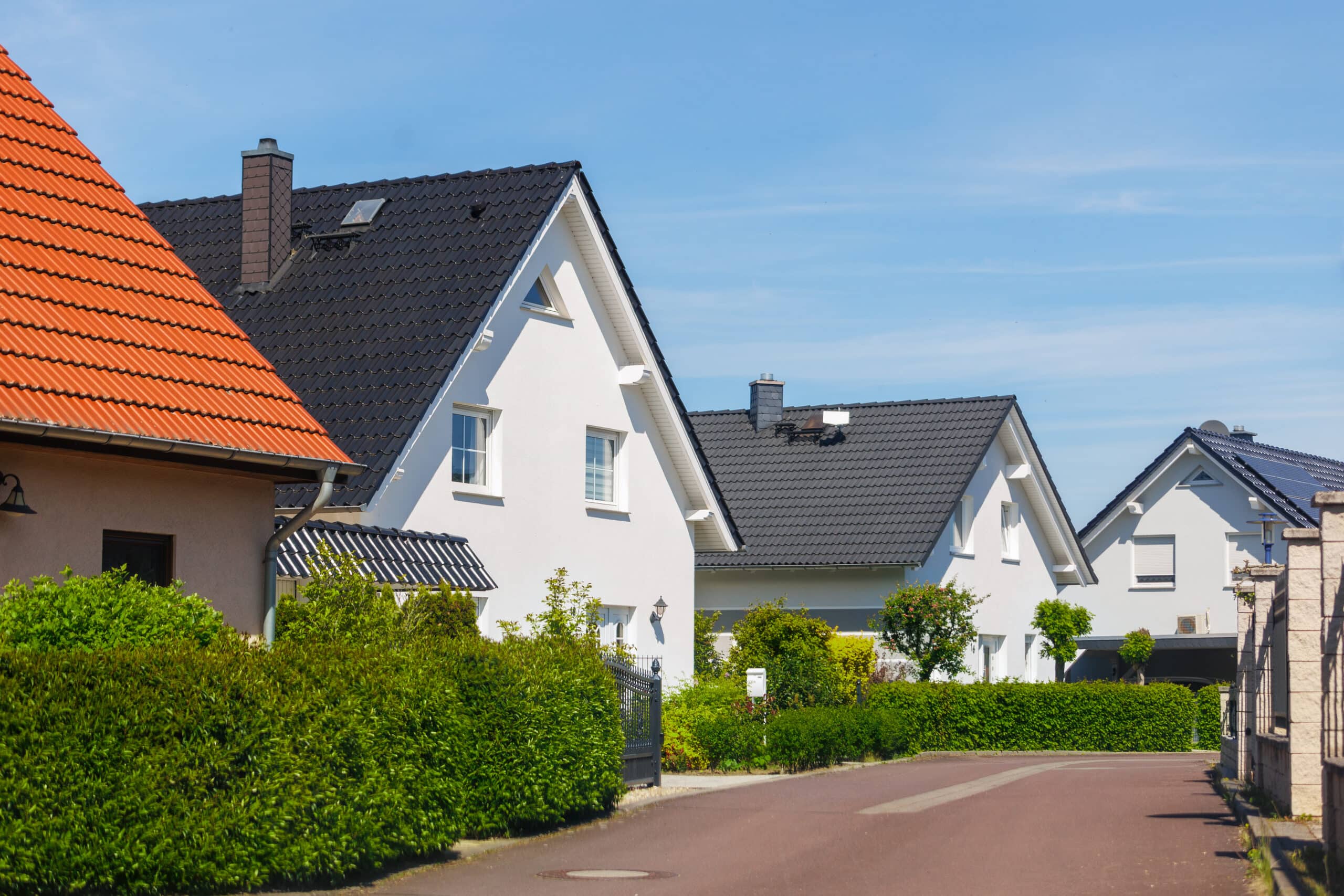Immobilienkauf und Kaufnebenkosten Einfamilienhäuser in einem deutschen Wohngebiet mit gepflegten Vorgärten.