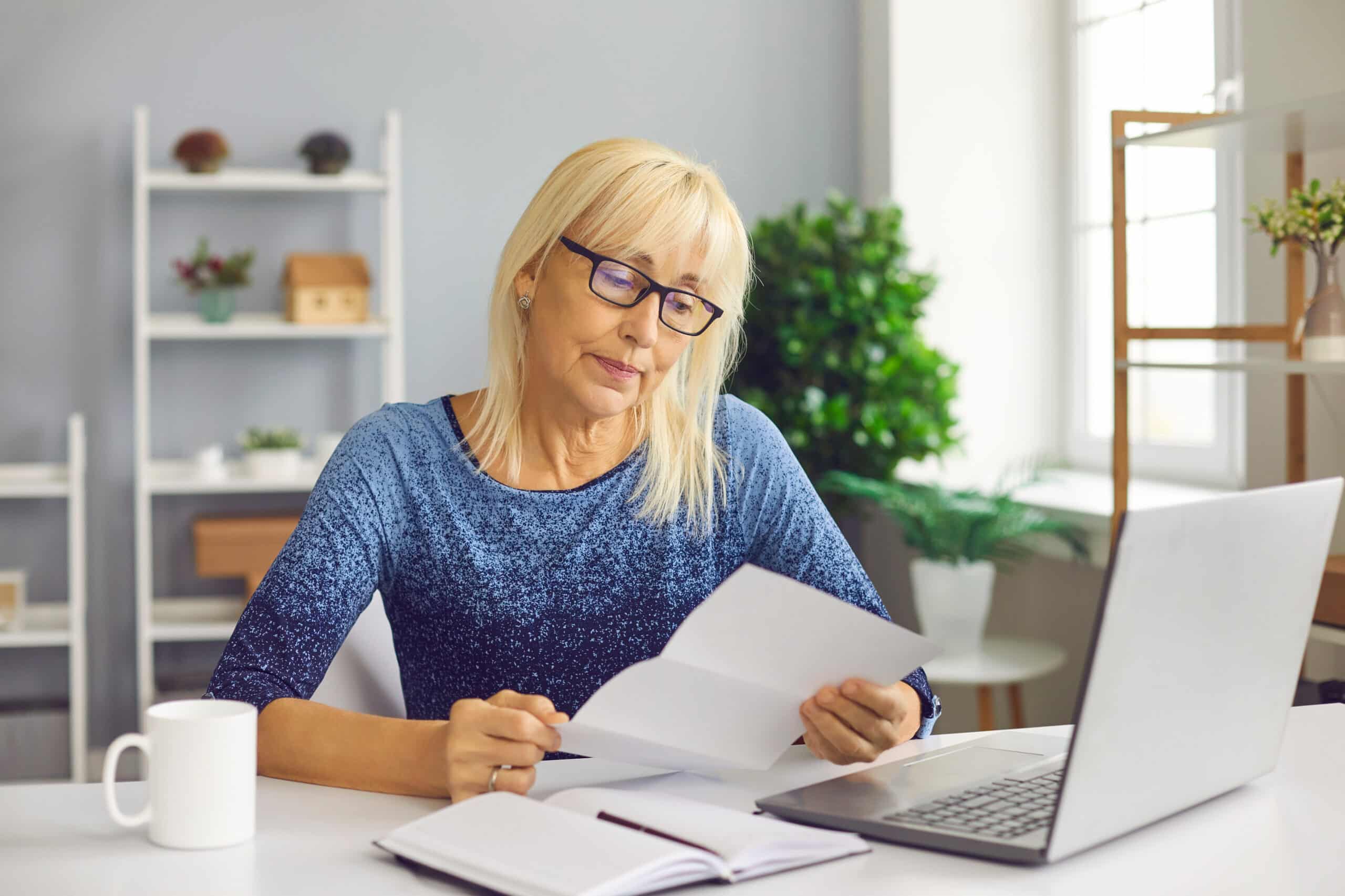 Nach der Kreditablehnung: Unterlagen prüfen Frau am Laptop liest konzentriert ein Schreiben und macht sich Notizen