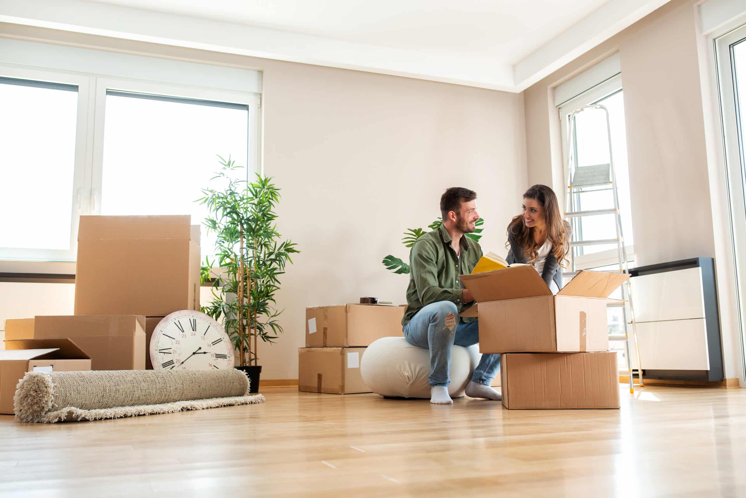 Umzug und Anschlussfinanzierung: Paar in neuer Wohnung Junges Paar mit Umzugskartons in einer hellen leeren Wohnung