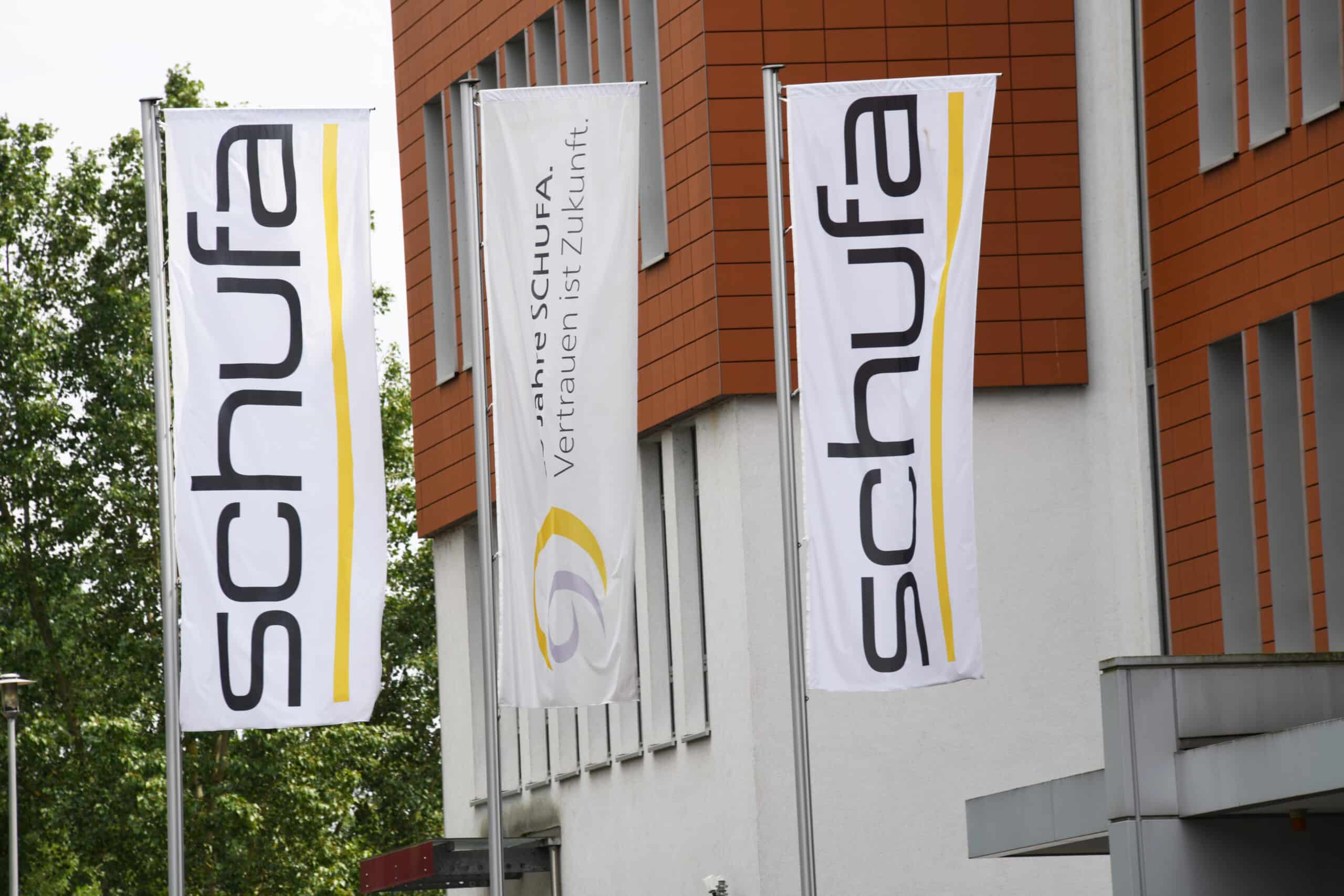SCHUFA: Flaggen am Firmengebäude Drei Flaggen mit SCHUFA-Logo vor einem Bürogebäude der Wirtschaftsauskunftei