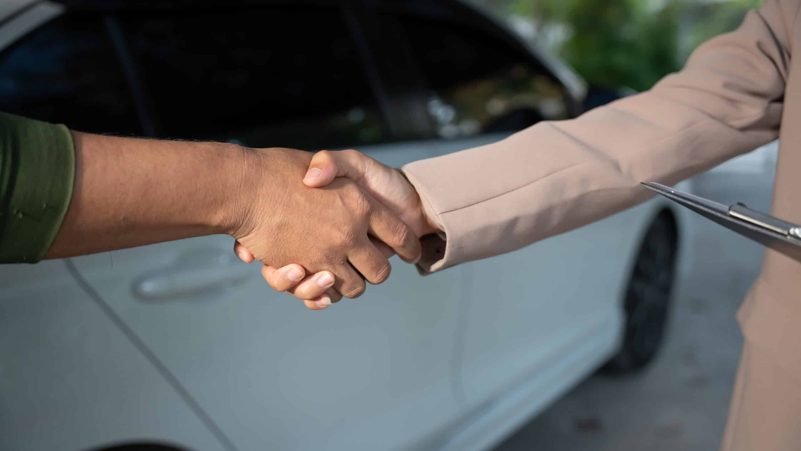 Autofinanzierung Vertragsabschluss Autokauf Handschlag Handschlag vor einem Auto nach Abschluss einer Autofinanzierung